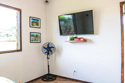 a room with a fan and a flat screen tv at Tahaa Cosy Home in Tautu