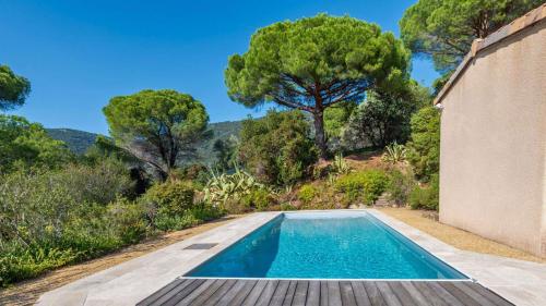 une piscine devant une maison avec des arbres dans l'établissement Villa églantine- Piscine- calme, au Lavandou