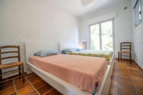 - 2 lits dans une chambre avec une fenêtre et 2 chaises dans l'établissement Villa églantine- Piscine- calme, au Lavandou