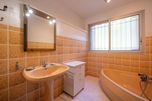 une salle de bain avec un lavabo, une baignoire et un miroir dans l'établissement Villa églantine- Piscine- calme, au Lavandou
