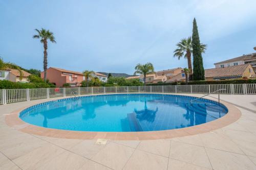 une grande piscine bleue avec une clôture et des palmiers dans l'établissement Mazet 6 a 7 pers Piscine Tahiti Park, au Lavandou