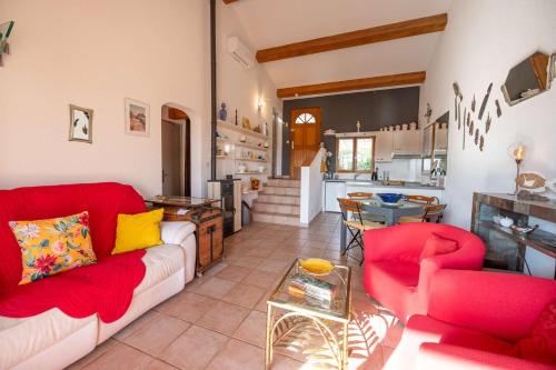 Il comprend un salon doté d'un mobilier rouge et une cuisine. dans l'établissement Maison climatisée pour 5 personnes , au clame , jardin arboré proche commerces, à Bormes-les-Mimosas
