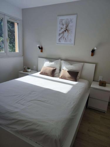 une chambre avec un grand lit blanc avec deux oreillers dans l'établissement T3- Rénové- Clim- Plages- Commerces, au Lavandou