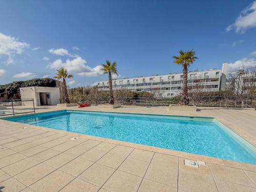 une piscine devant un immeuble avec des palmiers dans l'établissement T2 Résidence EDEN, Piscine , Idéale pour une famille de 4 personnes, au Lavandou