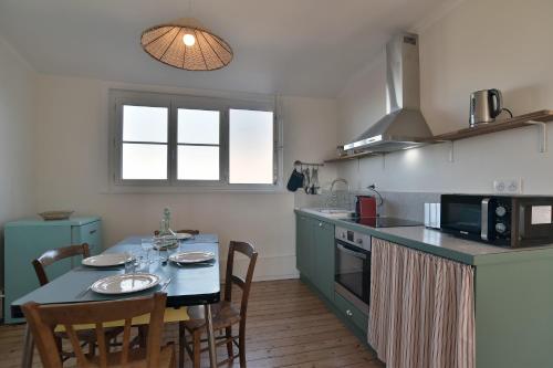 une cuisine avec une table avec des chaises et une salle à manger dans l'établissement Le Nid Malouin - A 350 m de la plage, à Saint-Malo