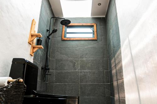 uma casa de banho com um chuveiro, uma janela e um WC. em Tahaa Cosy Home em Tautu