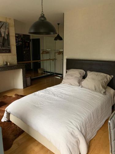 une chambre avec un grand lit avec des draps blancs dans l'établissement 3 chambres chez l'habitant, à Salleboeuf