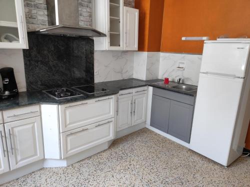 une cuisine avec des armoires blanches et un réfrigérateur blanc dans l'établissement COUNTRY Cottage, à Craponne-sur-Arzon