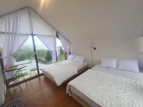 two beds in a room with a large window at cabin view gunung in Kejajar