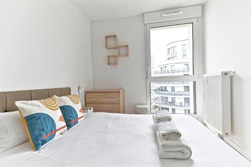 - une chambre blanche avec une grande fenêtre et un lit dans l'établissement Spacieux 3 chambres avec balcon, à Colombes