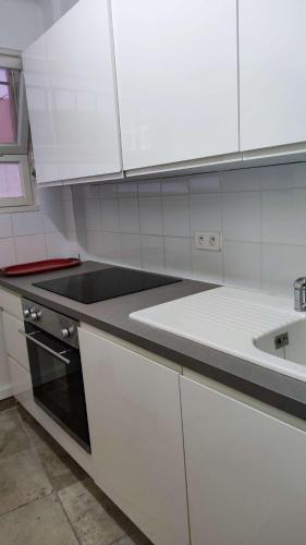une cuisine avec des armoires blanches et un évier dans l'établissement Le Marbello- Vue mer- Plages- Commerces, au Lavandou