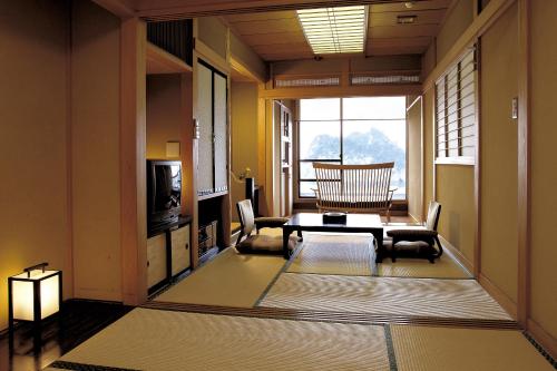ein Wohnzimmer mit einem Tisch, Stühlen und einem TV in der Unterkunft Umibenokakureyu Seiryu in Nishiizu