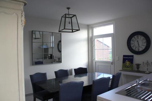 a dining room with a table and a clock on the wall at Ferme de Canny in Canny-sur-Matz