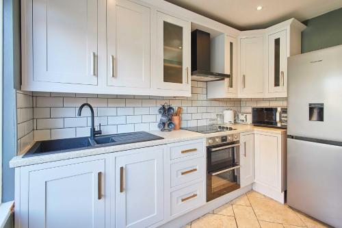 a kitchen with white cabinets and a sink and a refrigerator at Host & Stay - Wellington Street in Ripon