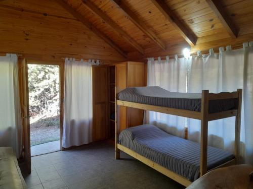 two bunk beds in a cabin with a window at Cabaña SOLO 42 - Villa Lago Meliquina in Villa Meliquina
