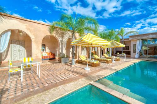a house with a swimming pool with a table and umbrella at Palais Noryalis in Tillouna