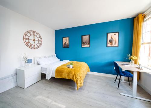 a bedroom with blue walls and a bed with a yellow blanket at Open Mind Property - Hot Tub, 8 Guests & Free Parking in Portsmouth