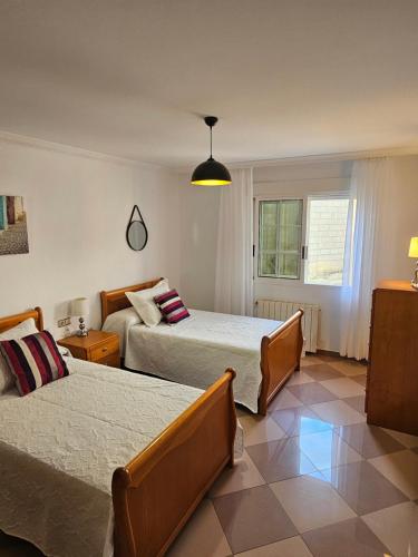 a bedroom with two beds and a window at Apartamento Priorato in Isla de Arosa