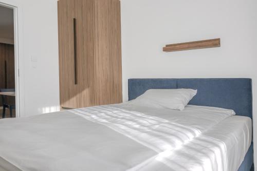 a bed with white sheets and a wooden cabinet at Noli Gdansk Wrzeszcz in Gdańsk