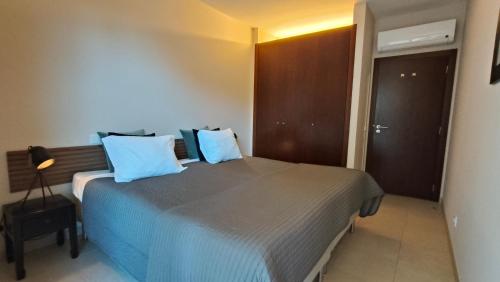 a bedroom with a large bed with blue pillows at Oasis by Templesuites - Praia da Rocha in Portimão