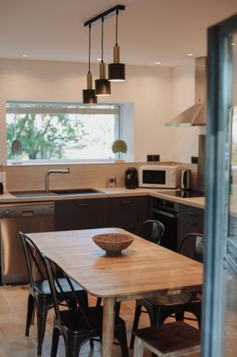 une cuisine avec une table en bois et quelques chaises dans l'établissement La Manova Nature&Détente SPA Sauna Bain Nordique Jacuzzi, à Bourges