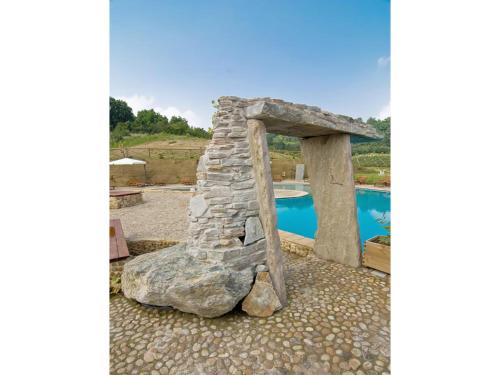 a stone fireplace sitting next to a swimming pool at Fattoria Delle Vignole in Sommariva Perno
