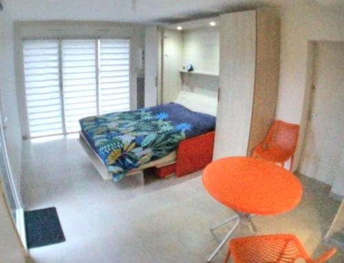 - une chambre avec un lit et une chaise orange dans l'établissement Studio avec jardin MER à proximité!, à Saint-Malo