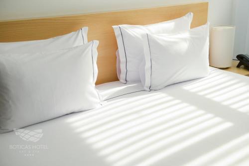 a bed with white pillows on top of it at Boticas Hotel Art & SPA in Boticas