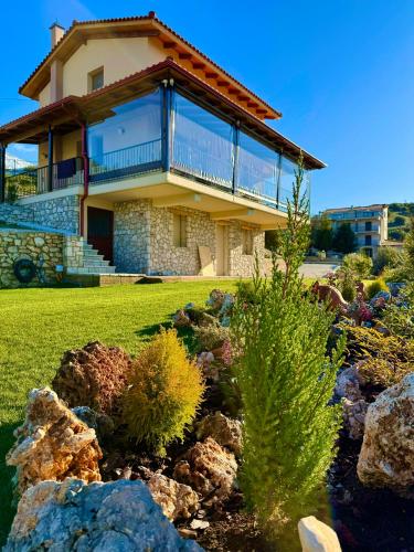 a house with a balcony and a yard with rocks at Alexi's House in Kalavrita