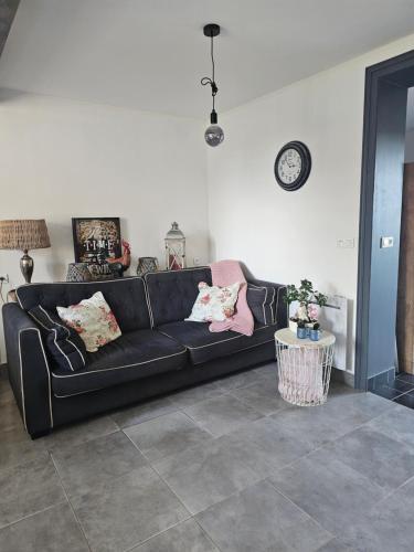 a black couch in a living room with a table at au Petit Paradis in Sainte-Gauburge-Sainte-Colombe