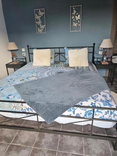 a bed with a gray blanket on top of it at au Petit Paradis in Sainte-Gauburge-Sainte-Colombe