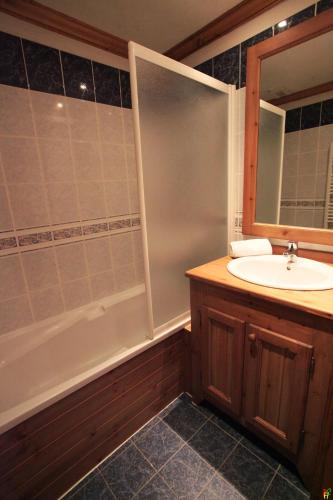 a bathroom with a sink and a shower with a mirror at Ancolies Val Thorens in Val Thorens