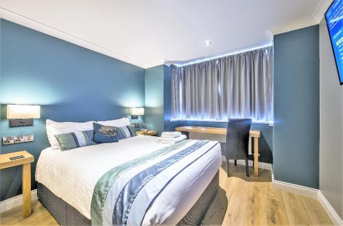 1 dormitorio con paredes azules, 1 cama y escritorio en Dolphin Rooms, en Cleethorpes