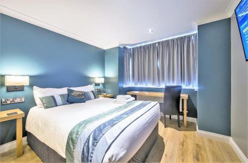 a bedroom with blue walls and a bed and a desk at Dolphin Rooms in Cleethorpes