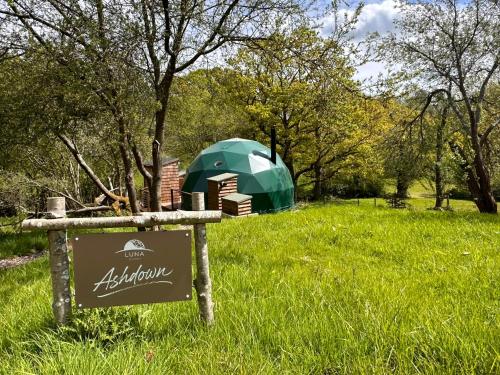 a sign with a green umbrella in a field at Luna Domes in Chiddingstone