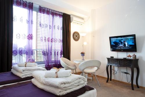 a living room with three beds and a table and a television at Belle Apartments-Elegance Apartments in Belgrade