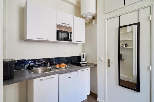 une cuisine blanche avec un évier et un micro-ondes dans l'établissement Le Petit Cernay - Studio - 5 mins Caves Champagne, à Reims