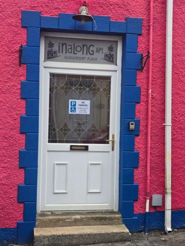 a blue wall with a white door in front of a building at Inalong - Quirky property with sea views above an Ale House in The Mumbles