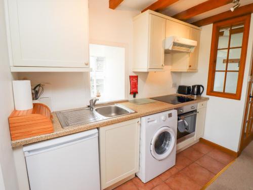 a kitchen with a sink and a washing machine at The Bothy in Lowick