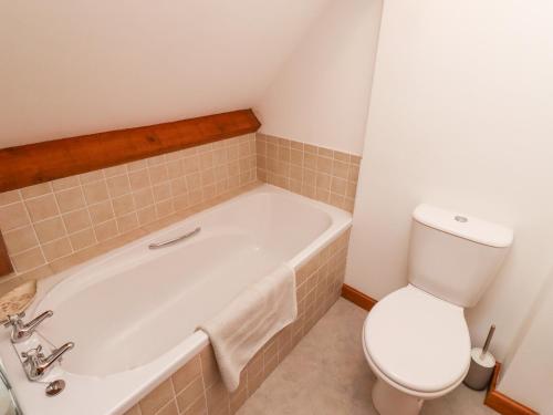 a bathroom with a white tub and a toilet at The Bothy in Lowick