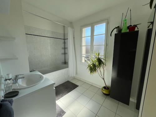 a white bathroom with a sink and a bath tub at Villa Hésperides 5 mins de Disneyland Paris in Magny-le-Hongre