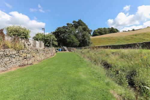 a stone wall next to a grassy field at Wend Gardens Studio Carleton Skipton Pet Friendly in Skipton
