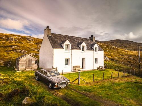 an old car parked in front of a white house at 2 Carrigreich in Scalpay