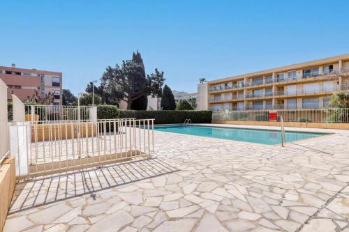 une clôture autour d'une piscine dans un bâtiment dans l'établissement Studio neuf bord de mer Le Lavandou - Piscine - Tennis - Boulodrome dans la résidence, au Lavandou