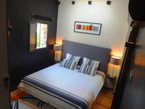 ein Schlafzimmer mit einem Bett mit zwei Kissen und einem Fenster in der Unterkunft Les Olives in Uzès