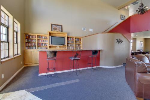 a room with a bar with stools and a tv at Overgaard Condo with Balcony, Near Hiking and Golfing in Overgaard