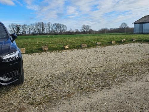 a car parked next to a field with hay bales at au Petit Paradis in Sainte-Gauburge-Sainte-Colombe