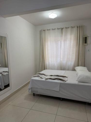 a white bedroom with a bed and a mirror at Itapuã - 4 Minutos da Praia - Quarto com Suíte in Vila Velha