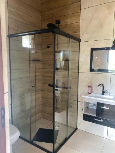 a shower with a glass door in a bathroom at Pousada Arco Iris in Gonçalves