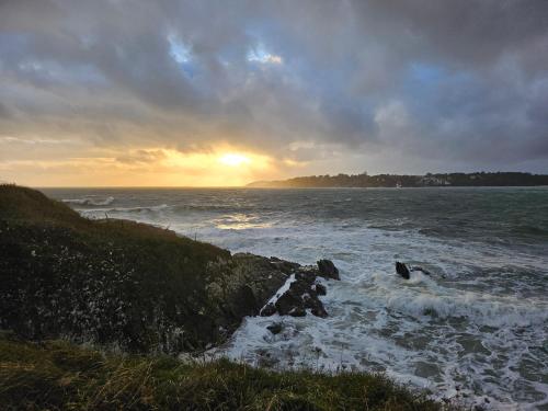 a sunset over the ocean with rocks in the water at Gîte Les mouettes qui caquètent in Moëlan-sur-Mer